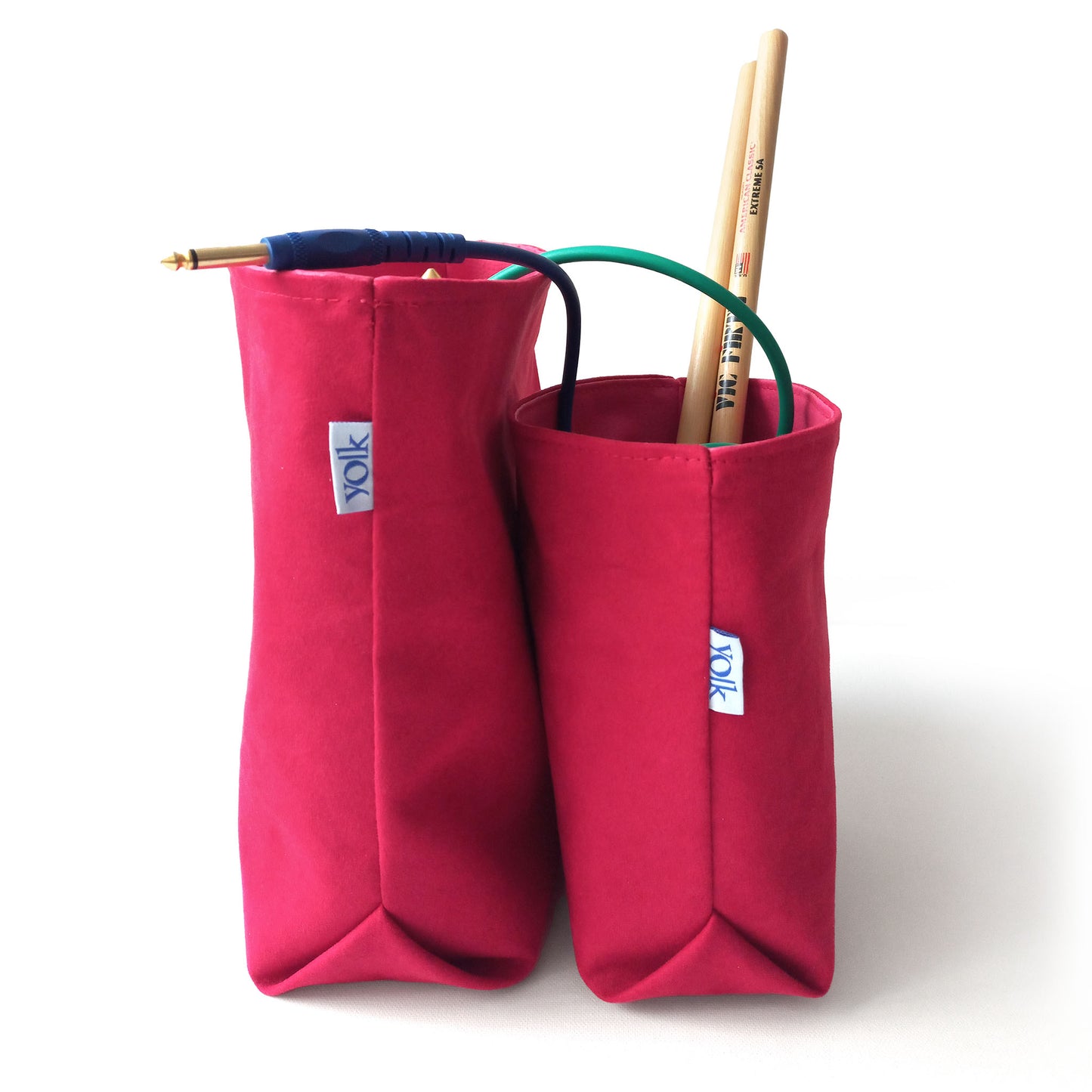 Two red fabric baskets filled with wires and drumsticks