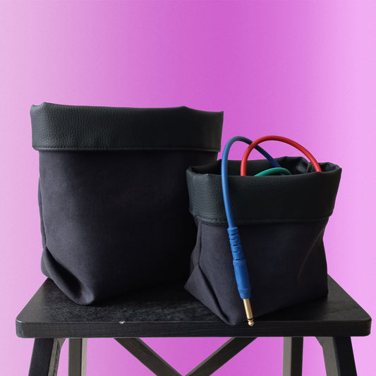 Two black colour baskets filled with wires on pink background