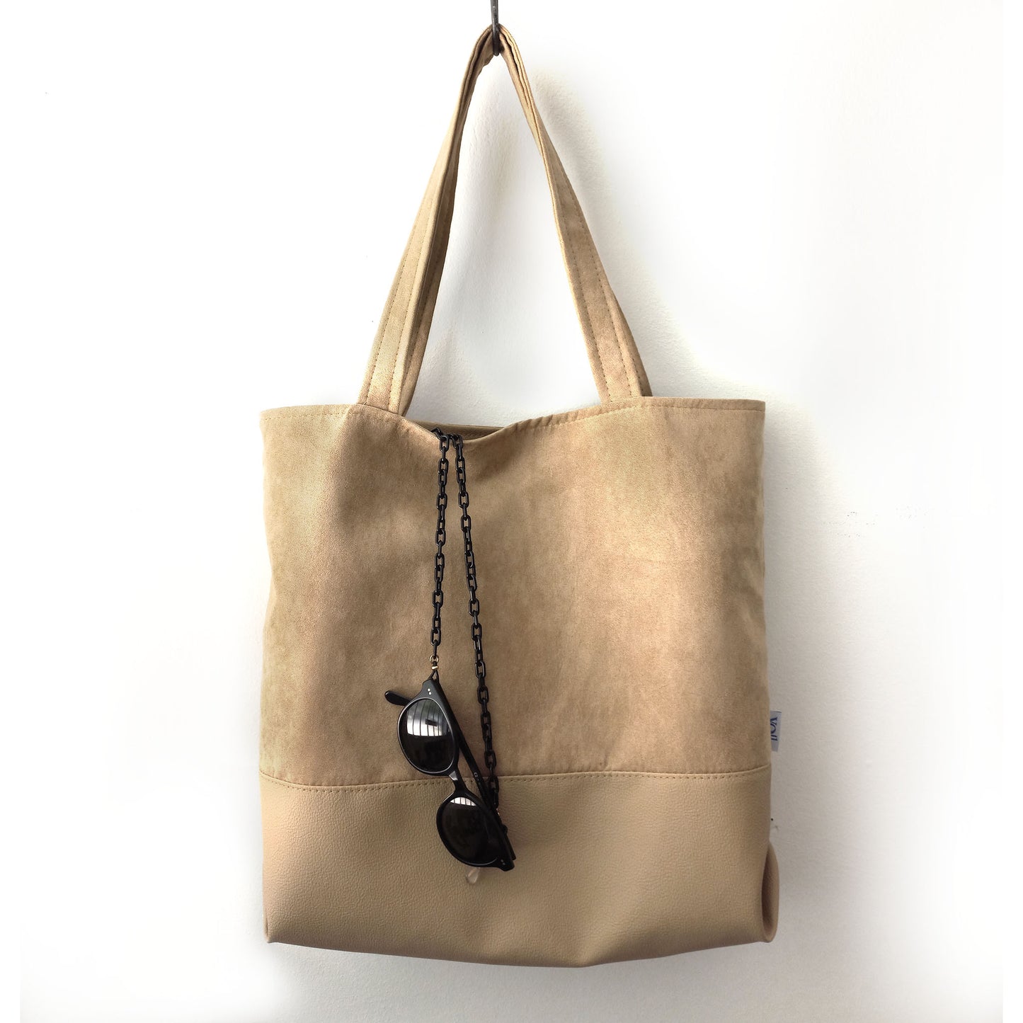 Handmade peanut butter color shoulder bag on a hanger with sunglasses