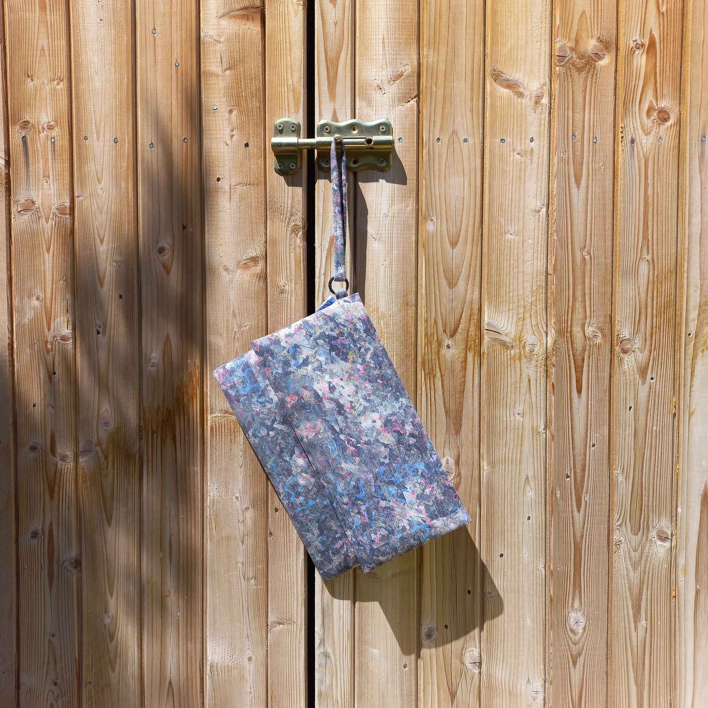 Vegan suede printed clutch bag hanging from a lock