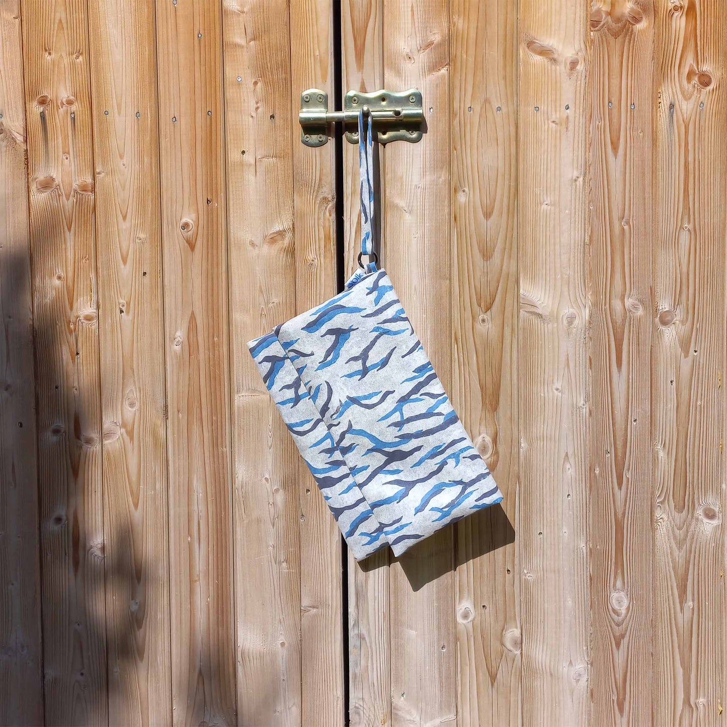Printed suede clutch bag hanging from a door lock