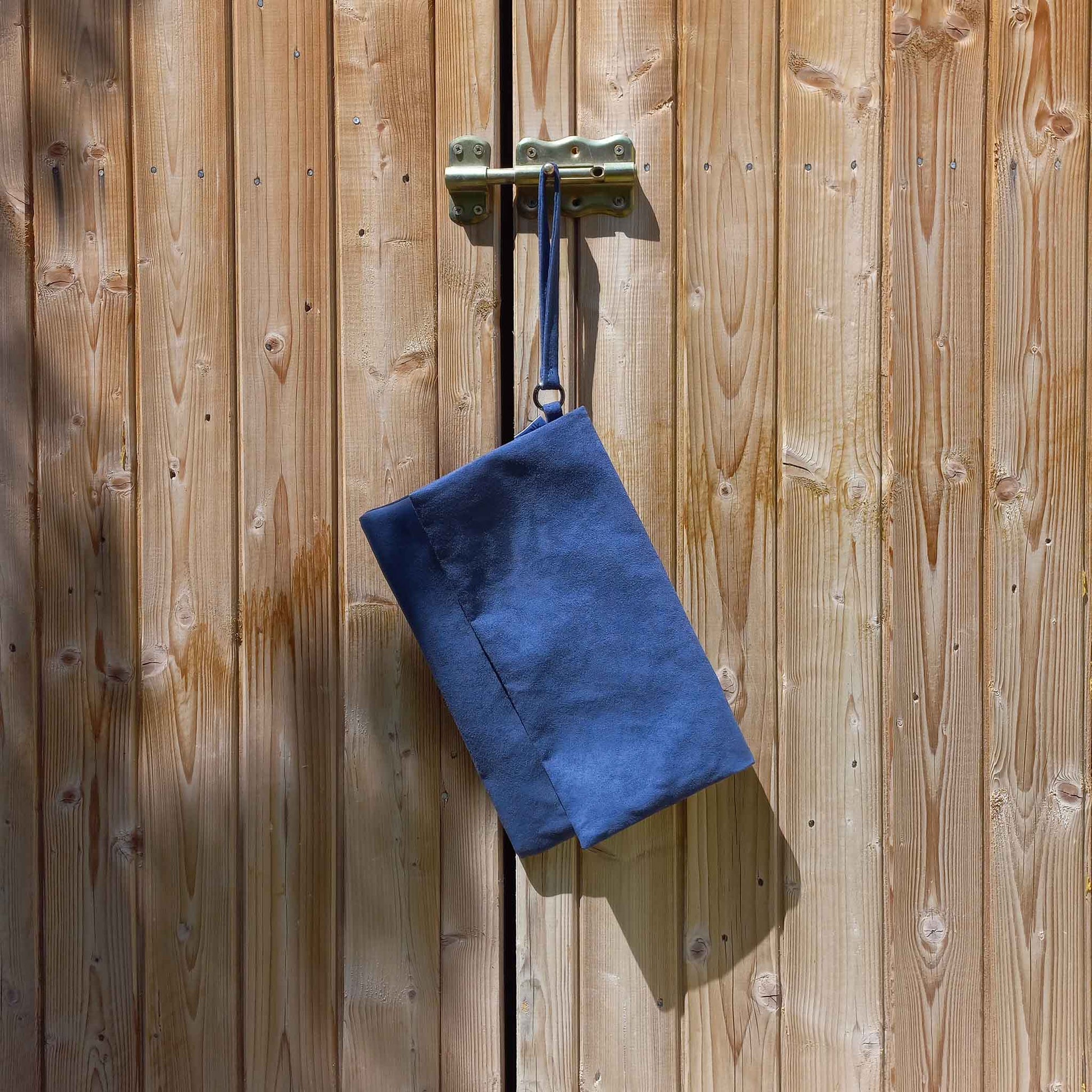 Blue suede clutch bag hanging from a shed lock