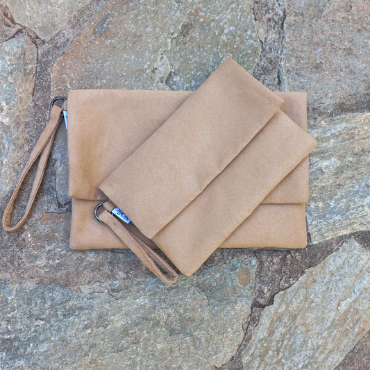 Small and large clutch bags on a stone floor.