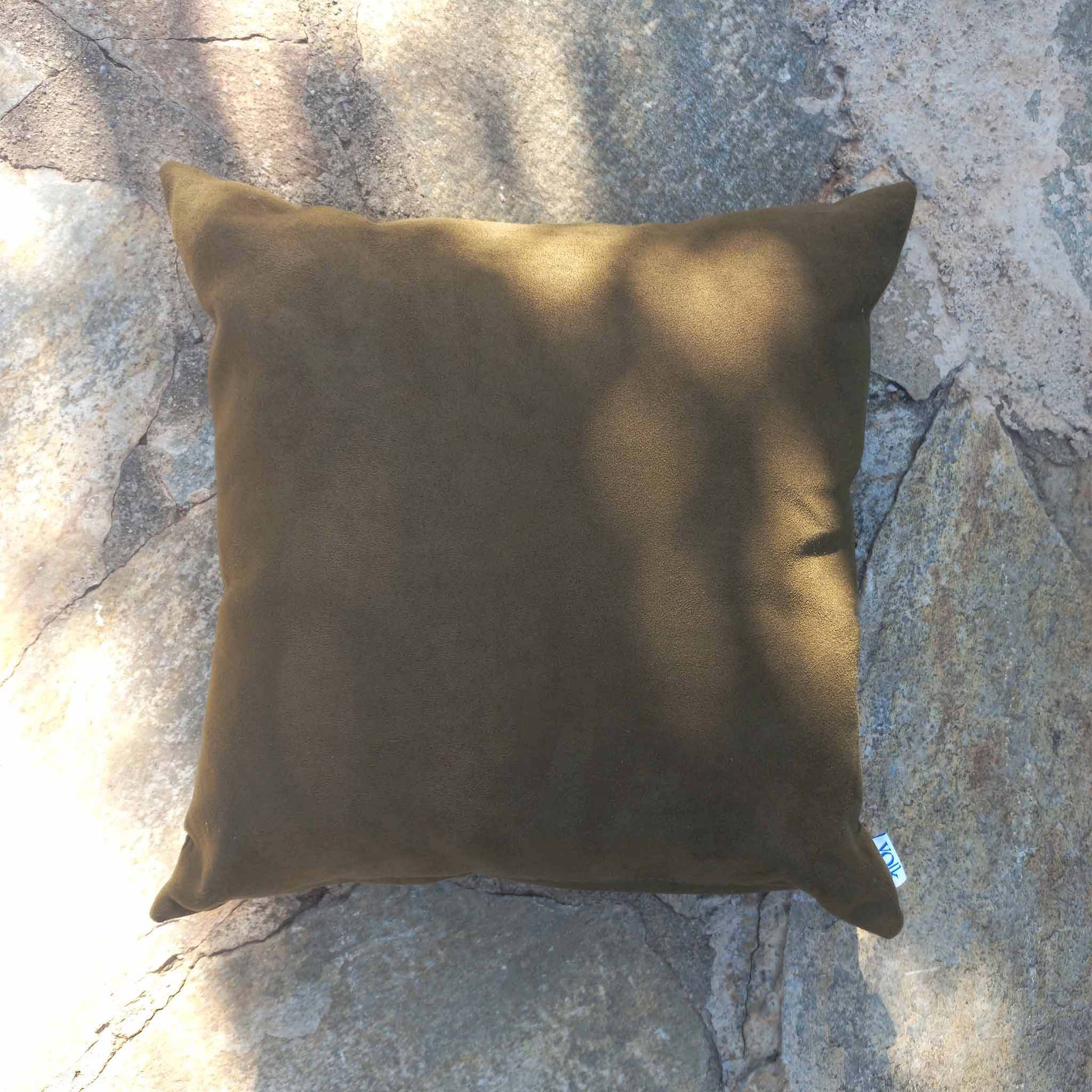 Dark green vegan suede cushion on a stone floor